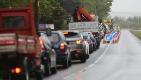 Vehicles wait in traffic at a set of roadworks.