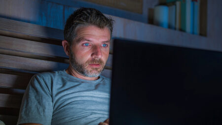 Man looking at laptop in bed