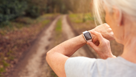 Elderly woman using smartwatch on country path