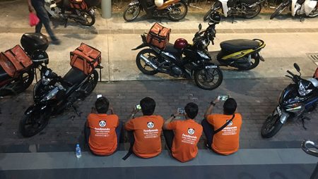 Motorcycle delivery drivers waiting by their bikes.