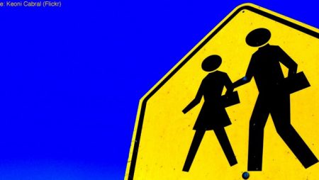 Road sign warning of people (represented by stereotypically dressed man and woman) crossing the road.