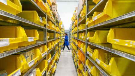 Worker walking between shelves filled with trays