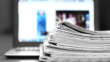 Pile of newspapers in front of a laptop