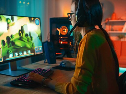 A girl playing online strategy video game on a computer.