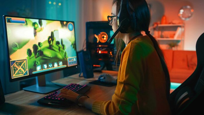 A girl playing online strategy video game on a computer.